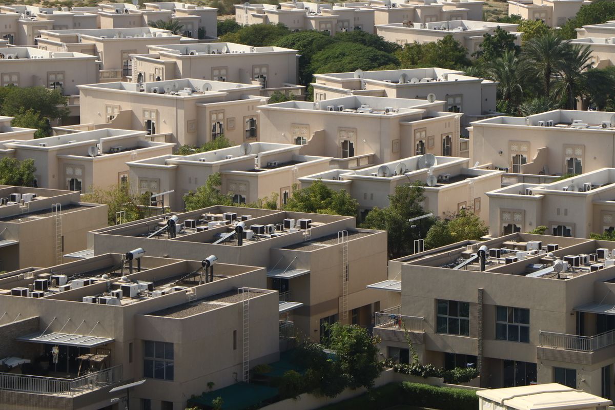 Aerial view of a Dubai residential community with modern buildings and greenery